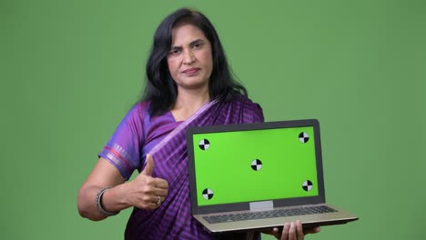 mature beautiful indian woman showing laptop and giving thumbs up