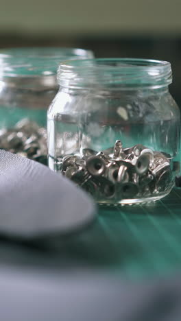 cu: skilled tailor takes hollow nails hat rivets and puts on cutting board near leather fabric closeup