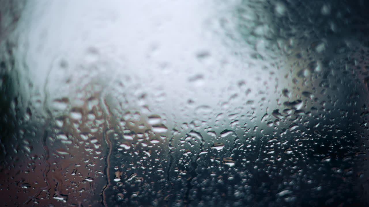 Close up of raindrops on a glass window with soft bokeh background