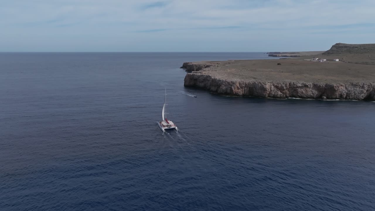 싱글 카타마란 보트 (single catamaran boat) 는 스페인 미노르카 주 폰트 덴 길 (pont del gil) 해안에서 정오에 항해합니다.