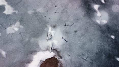 flying over a sandy beach, frozen lake, and a person walking on ice