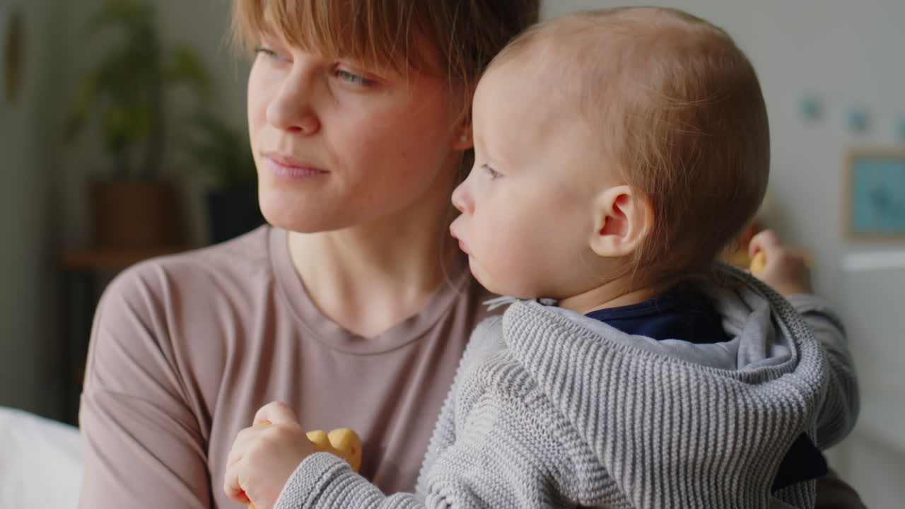 Happy Mom Holding Baby and Smiling at Home