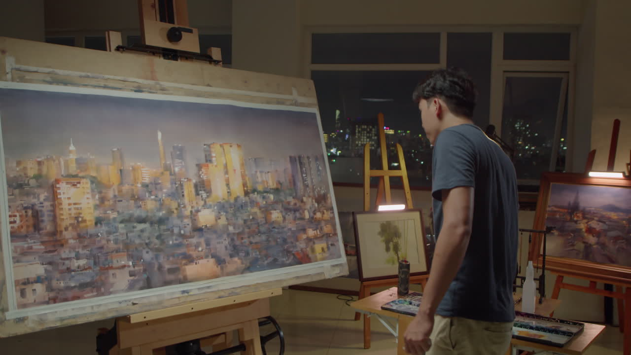 Asian Painter Drawing Night City on Canvas in Studio