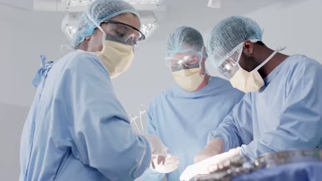 focused diverse male and female surgeons with face masks during surgery in slow motion, unaltered