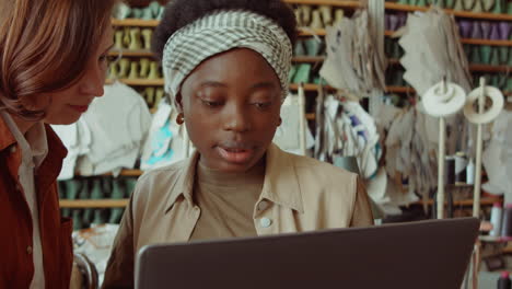 Cheerful-Women-Using-Laptop-and-Chatting-in-Shoemaking-Workshop