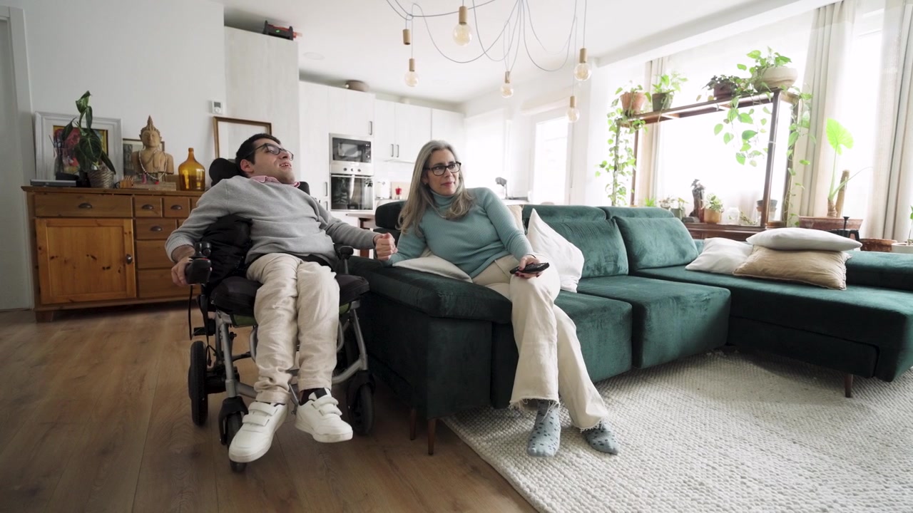 Donna seduta con uomo disabile in sedia a rotelle a casa