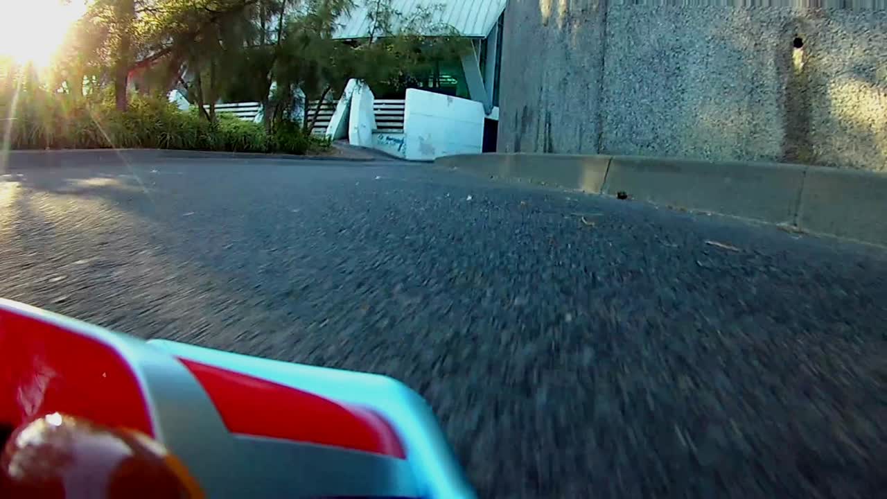 RC Radio control toy car racing on a real asphalt track with sun rays shinning through the natural trees