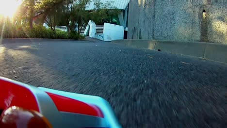 rc radio control toy car racing on a real asphalt track with sun rays shinning through the natural trees