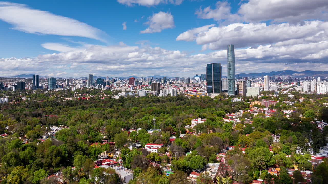 Drone hyperlapse showing Mexico City skyline from Viveros de Coyoacán, featuring lush urban forest and modern skyscrapers under cloudy sky