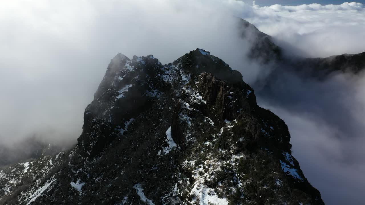 toma de drones del pico oscuro y negro de la montaña pico ruivo en madeira con nubes delgadas volando alrededor