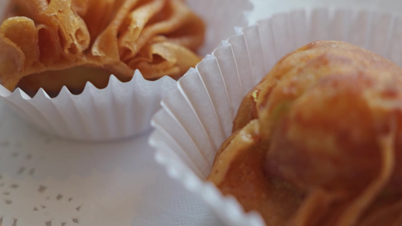 Primo piano di polpette di pesce tailandesi appena fritte con una superficie dorata e croccante, servite su un piatto come antipasto tradizionale tailandese salato