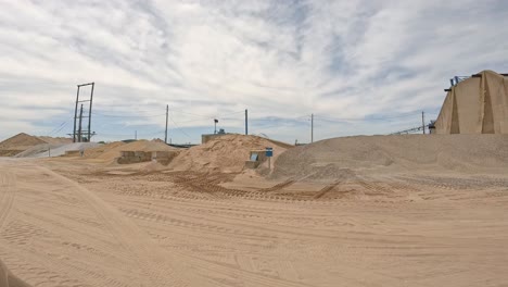 pov slowly driving through a gravel and sand depot along the mississippi river