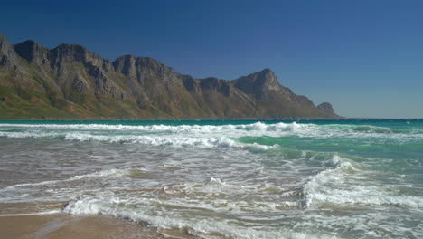 Koeel-Bay-Dappat-Se-Gat-beach-cinematic-windy-surf-waves-crashing-stunning-Kogel-Bay-Cape-Town-South-Africa-coastline-aqua-deep-blue-water-Gordon's-Bay-Garden-Route-pan-right