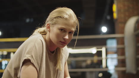 sleepy female boxer having rest at gym. fit girl making a pause on boxing ring