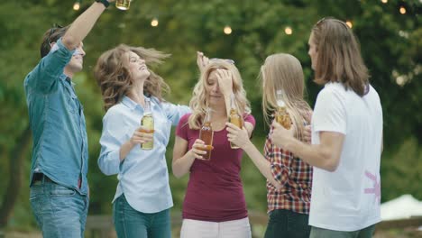 party. happy friends dancing and drinking outdoors.