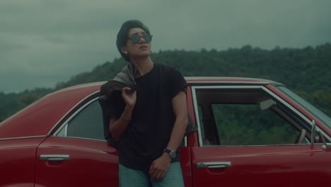 man leaning against a vintage red car