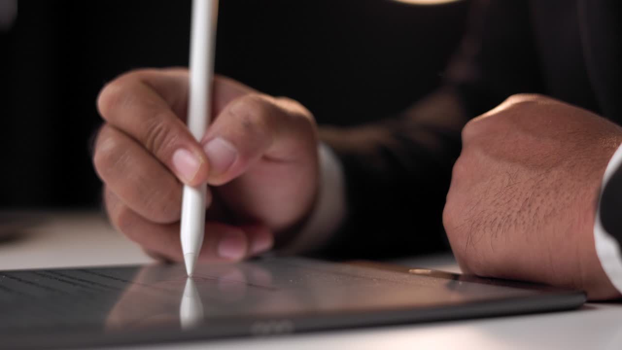 Close up businessman hand working electronic Signature on Tablet by Stylus at night. Write business agreement of contract. Man signing contract on tablet. Business and technology concept.