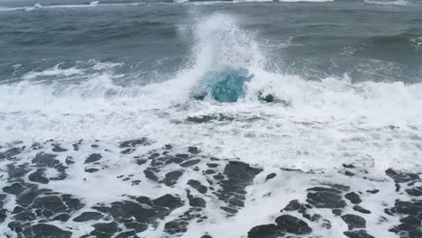 stunning drone shot of waves breaking on a beautiful ice rock at diamond beach in iceland