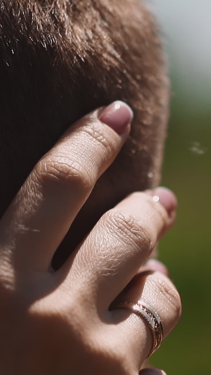 Woman hand strokes gently head of beloved man on blurred background closeup slow motion. Lovely young couple enjoys romantic date. Love relationship