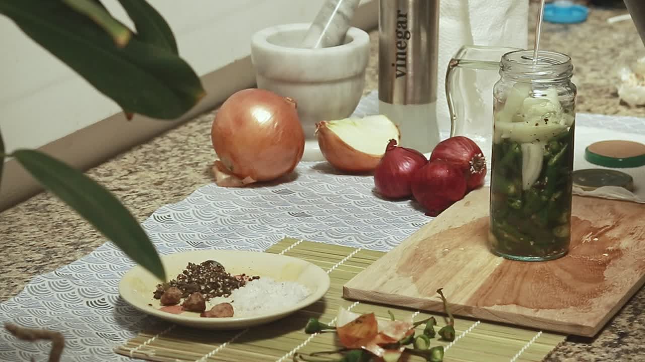 Adding a vinegar and water mixture to a jar of green chili and onions before tightening the lid, homemade pickles for healthy condiment