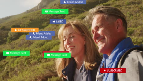 Animation-Von-Social-Media-Texten-Und--Symbolen-über-Einem-Kaukasischen-Paar-In-Den-Bergen