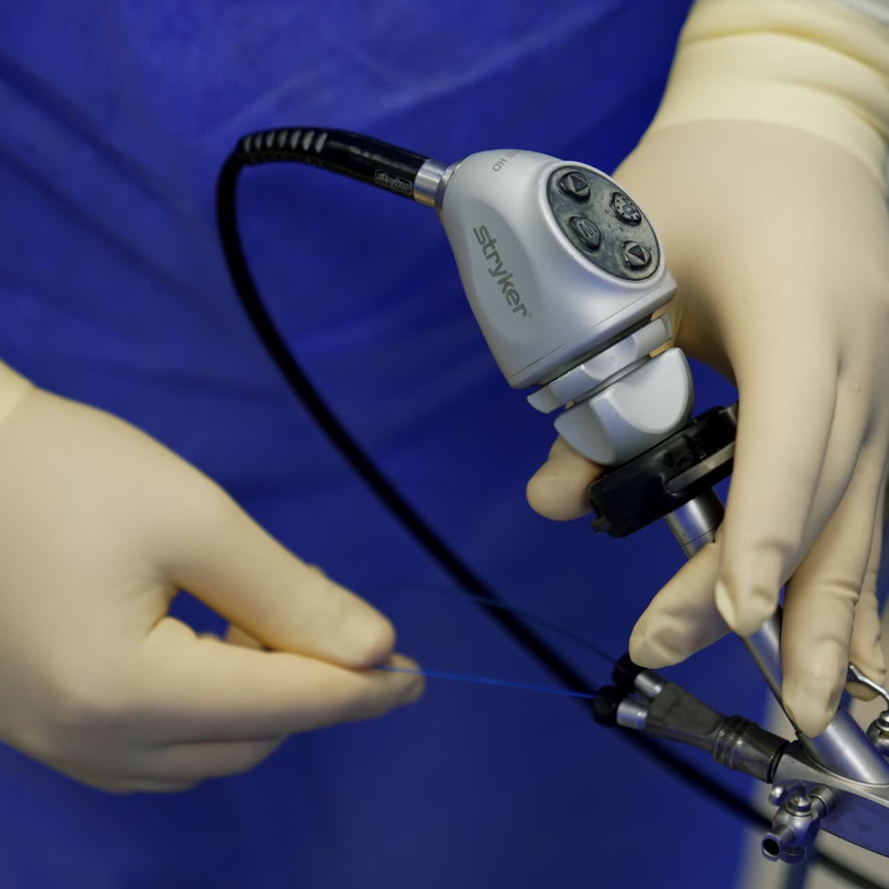 Doctor's hands wearing latex gloves holds the medical device. Surgeons take a wire and push it into the instrument. Close up