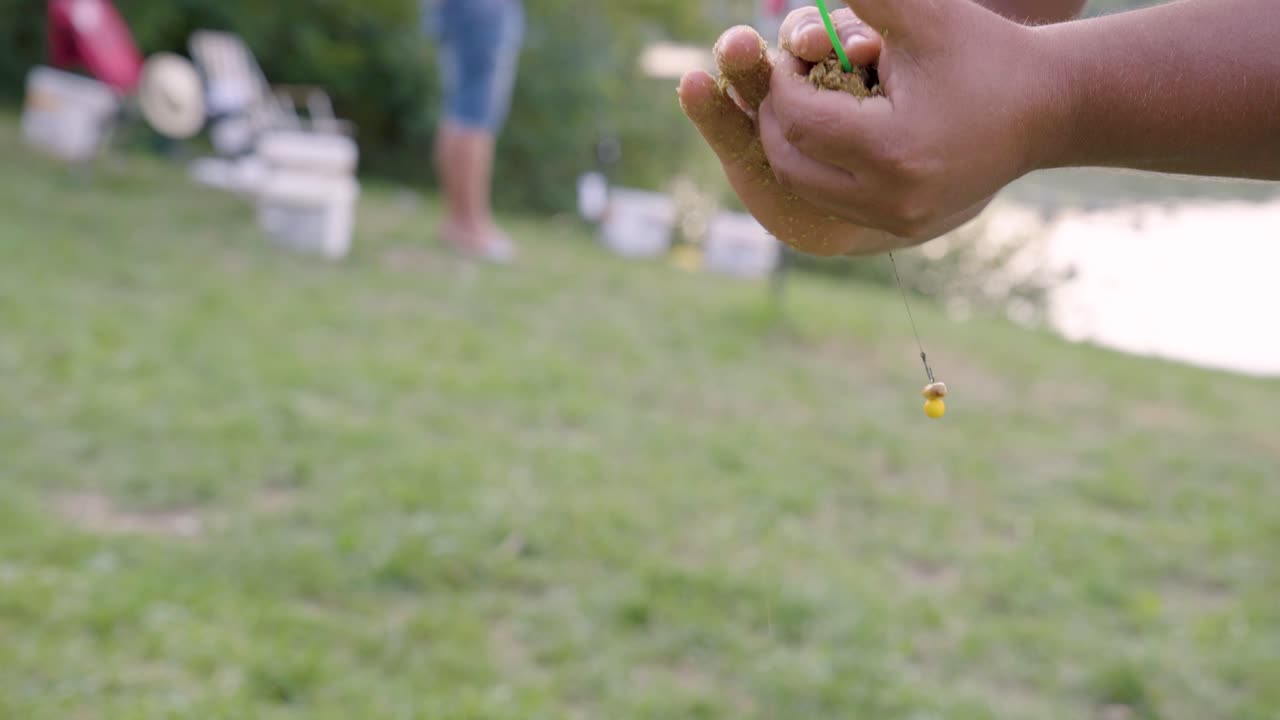 셔츠를 입지 않은 남자가 헝가리 바르보 호수 근처의 낚싯줄에 미끼 공을 부착합니다.