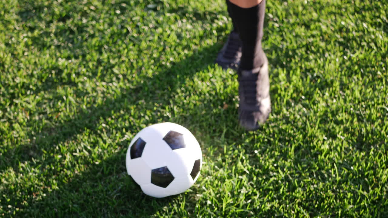 Nærbillede af en fodboldspiller, der dribler en fodbold i slowmotion under en konkurrencepræget kamp på en grøn sportsbane