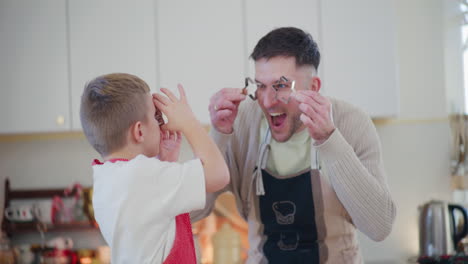 dad and son playfully bake christmas cookies together