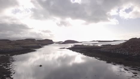 Low-aerial-shot,-above-the-sea-and-rock-pools,-flying-South-from-the-Island-of-Ulva-out-towards-the-ocean-and-the-Isle-of-Mul-on-an-overcast-day