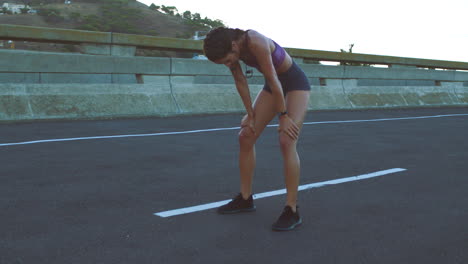 woman taking a break after a run on a city bridge.