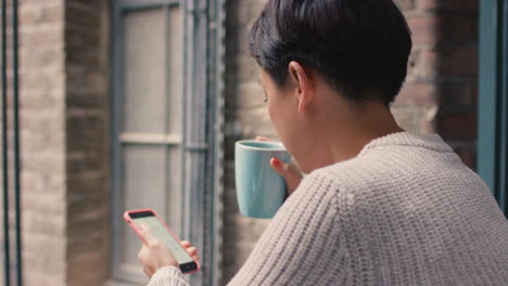 beautiful asian woman using smart phone outside drinking coffee on a break