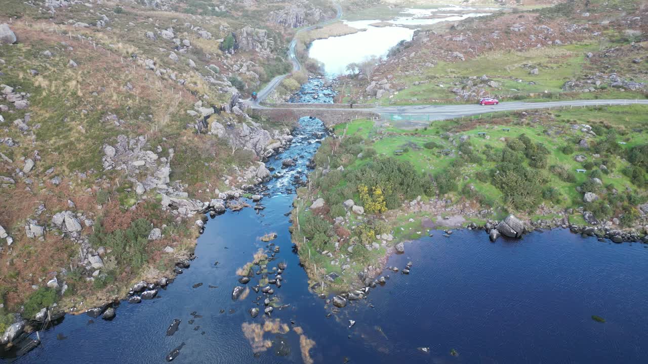 Wide panning aerial shot of Gap of Dunloe, Bearna or Choim&iacute;n, mountain pass in County Kerry, Ireland, with a bridge over the river Loe
