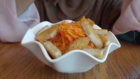 woman eating a salad with chicken and carrots