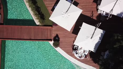 top down ascending shot of people eating on luxury villa terrace on poolside