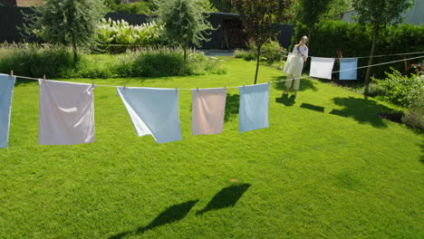 woman hanging clothes on clothesline in backyard garden