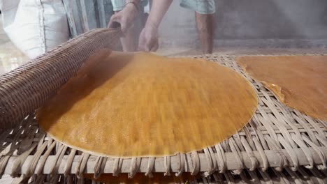 Close-up-of-person-making-traditional-banh-trang-cake-in-wooden-table