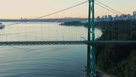 drone aerial shot flying back away from the lions gate bridge during golden hour in vancouver