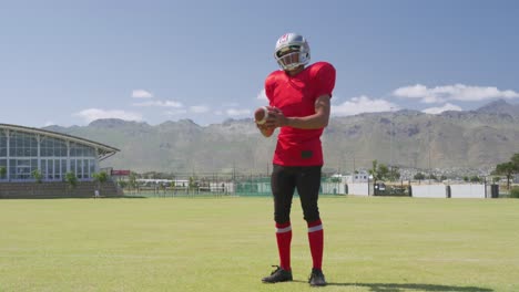 american football player standing with helmet and ball