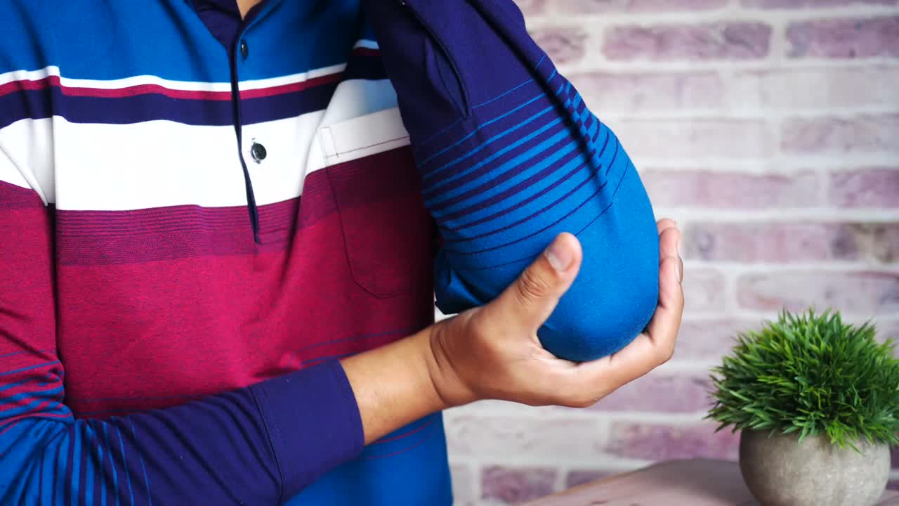 hombre sosteniendo su codo dolorido