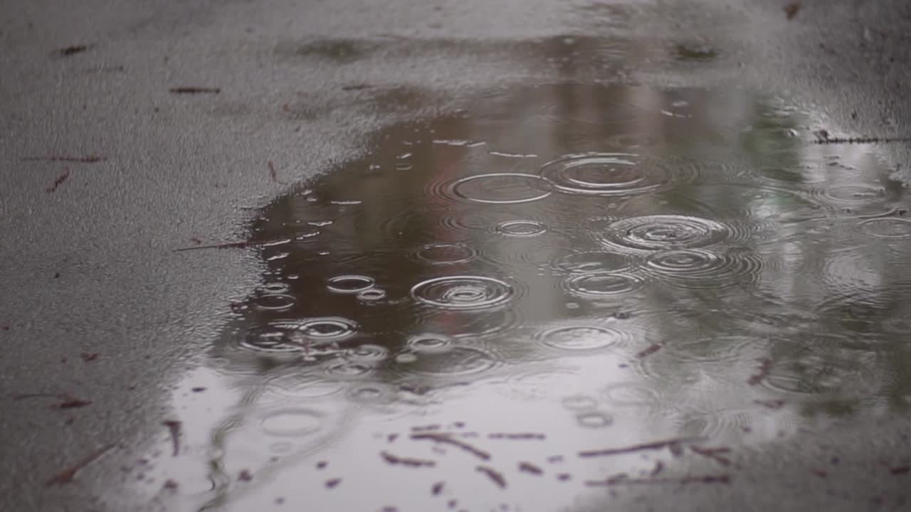 Slow motion footage of light rain on asphalt
