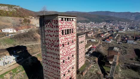 altas torres de fábrica abandonada, paredes pintadas con bichos rojos cerca de perrenjas en albania