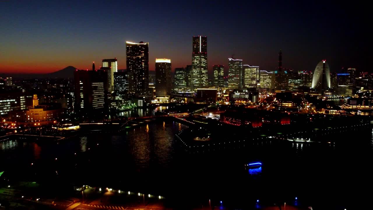 Twilight cityscape with illuminated buildings along the river, clear sky