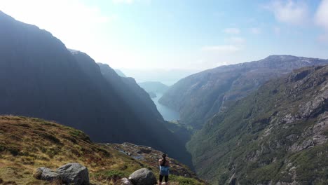 Rückwärtsbewegung-über-Dem-Kopf-Einer-Schönen-Frau,-Die-Auf-Einer-Klippe-In-Der-Herrlichen-Dramatischen-Norwegischen-Berglandschaft-Steht-–-Silhouette-Einer-Frau-Vor-Berglandschaft-Am-Ende-Des-Clips-–-Kiellandbu-DNT-Trail