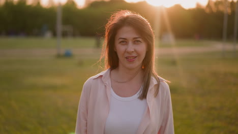 Cheerful-woman-in-casual-clothes-turns-head-on-sunset-lawn