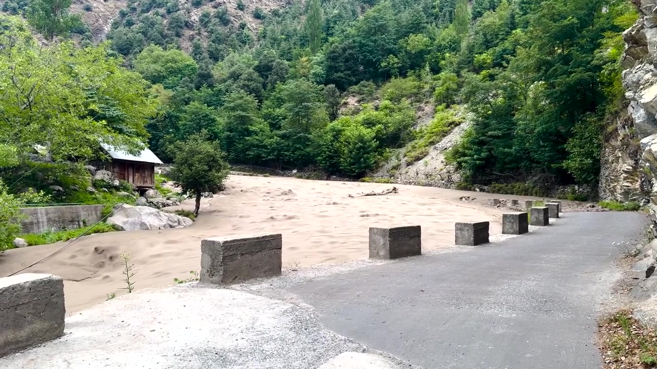 Air Banjir Berlumpur Meluap di Samping Jalan Pegunungan Melalui Lembah Berhutan di Kashmir