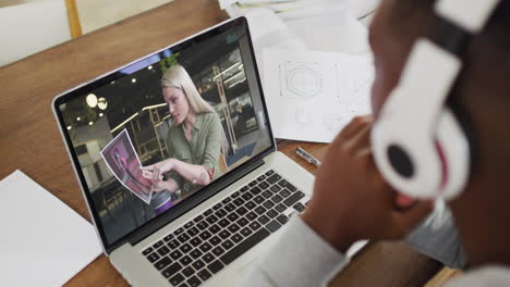 african american male college student wearing headphones having a video call on laptop at home