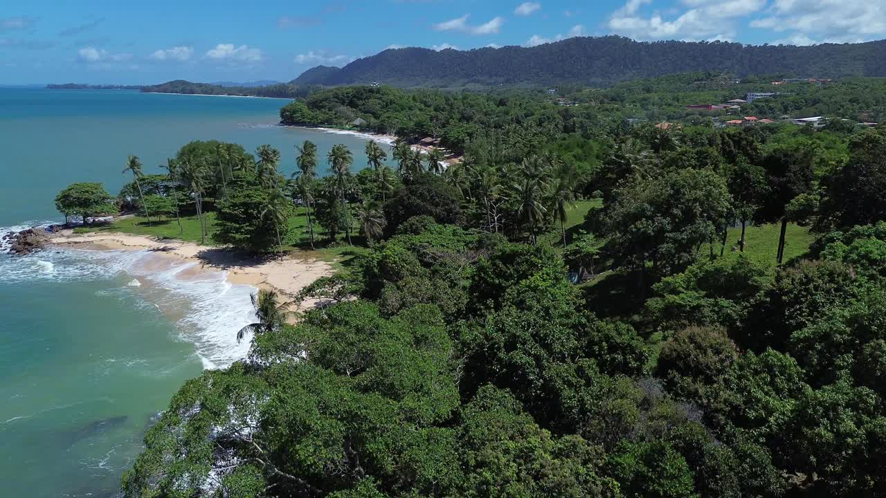 Aerial drone view rising above dense green jungle to reveal remote secluded beaches on Koh Lanta Thailand, featuring crystal clear water, tropical coastline and pristine travel destination paradise