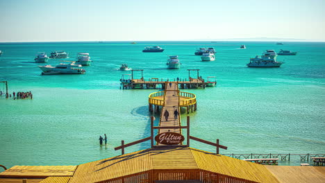 gente vadeando en el agua del mar rojo con yates anclados en orange bay en hurghada, egipto - lapso de tiempo