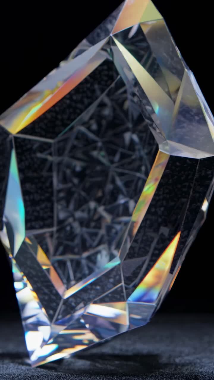 Close-up video of a rotating crystal with intricate facets reflecting light, captured from a low